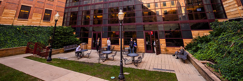 Students seated outside of the State Farm Hall of Business building on a sunny day.